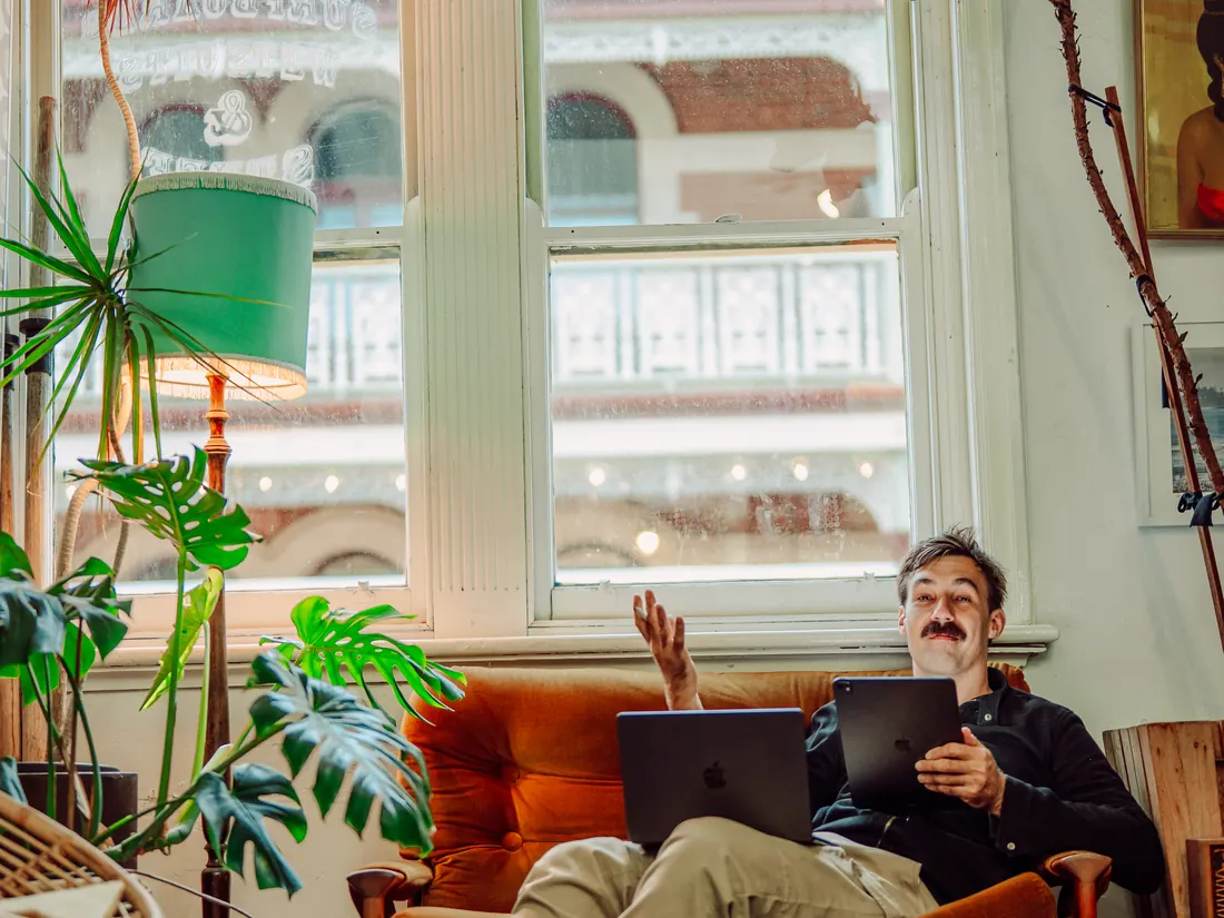 Sev on a couch with a laptop, mid-explanation