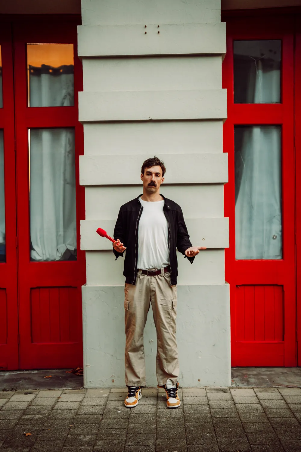 Sev standing between two red doors on a weatherboard shopfront