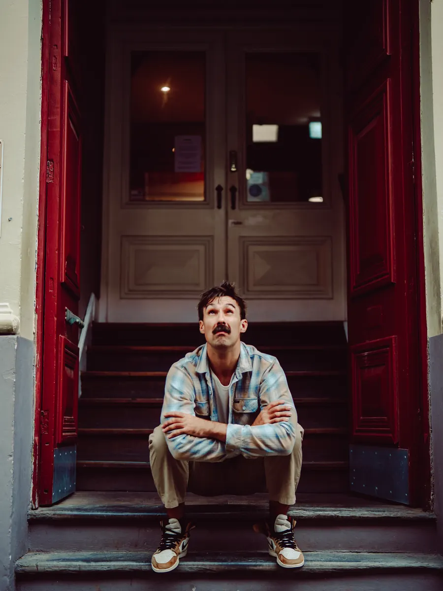 Sev sitting on the front steps of a red doorway